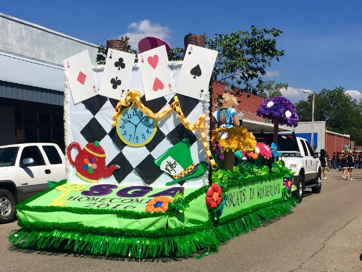 a parade float is decorated with flowers and cards on it's side, while people are walking down the street