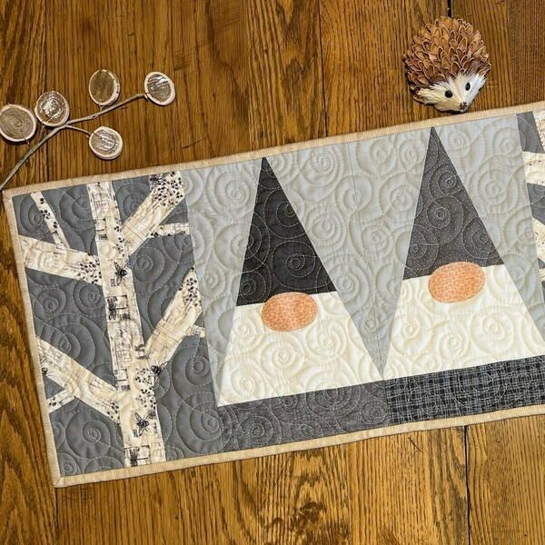 a quilted placemat with two gnomes on it and some coins next to it