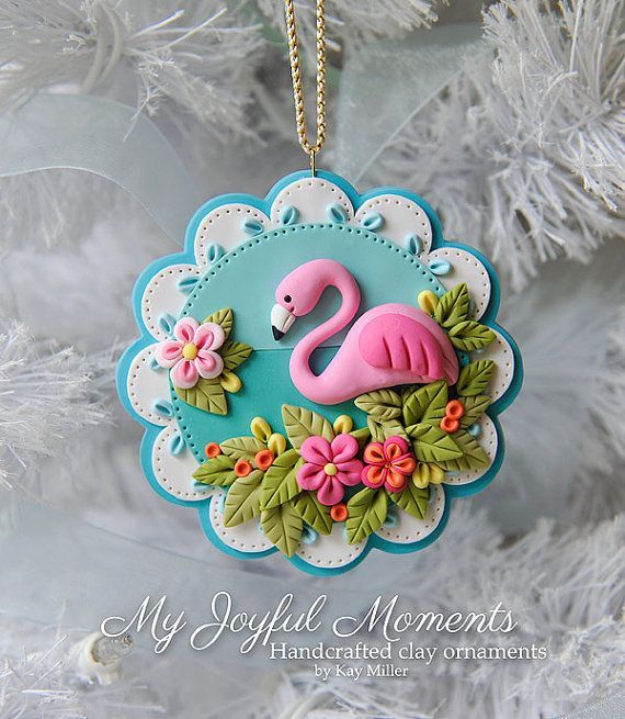 a pink flamingo ornament hanging from a christmas tree with flowers and leaves