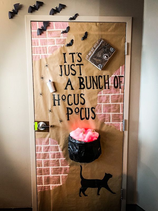 a door decorated to look like a house with a cat on it and bats flying around