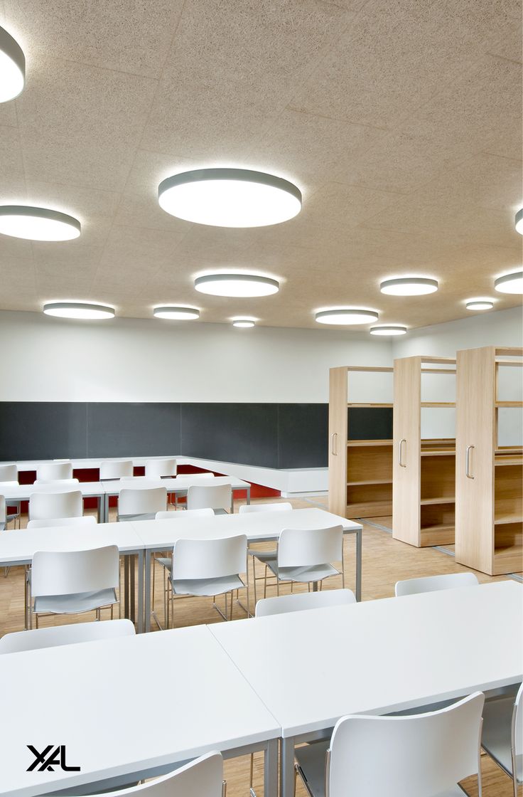 an empty classroom with white tables and chairs