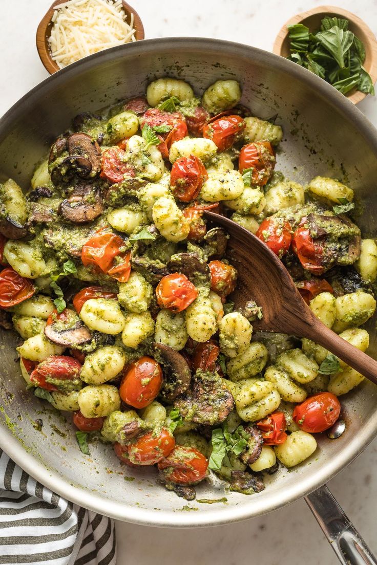 a pan filled with broccoli and tomatoes on top of a table next to some parmesan cheese