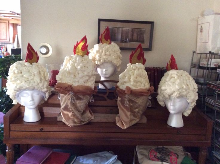 four white headdresses with red and yellow hats on them sitting on a table