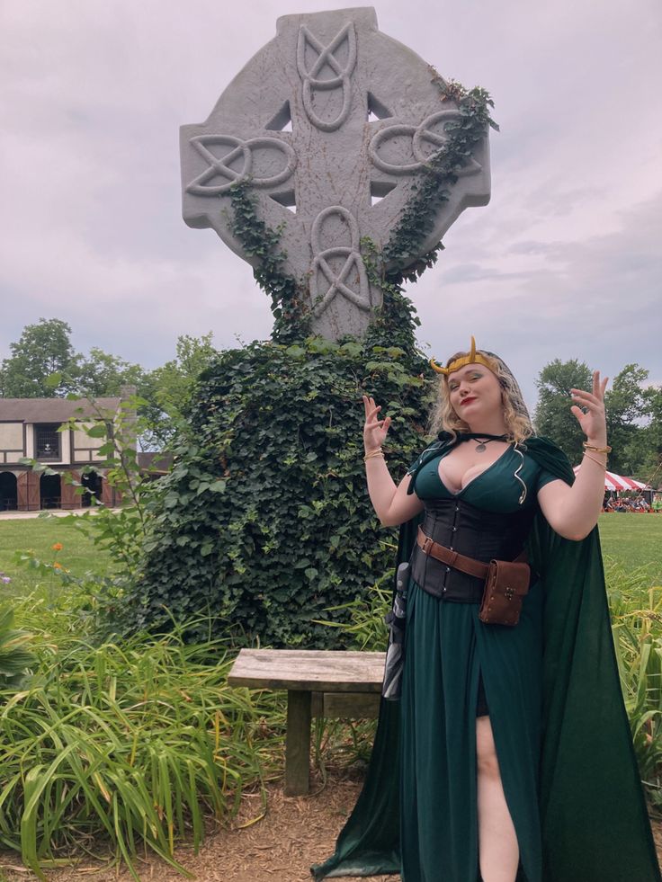 a woman in a green dress standing next to a cross