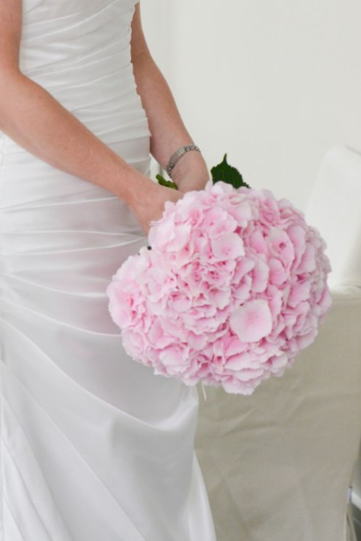 a bride holding a bouquet of pink flowers