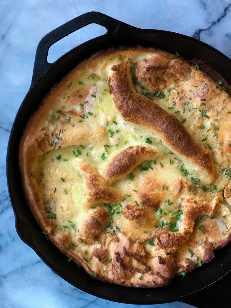 a cheesy dish in a cast iron skillet on a marble countertop