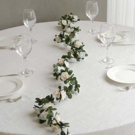 the table is set with white plates and silverware, along with flowers on it