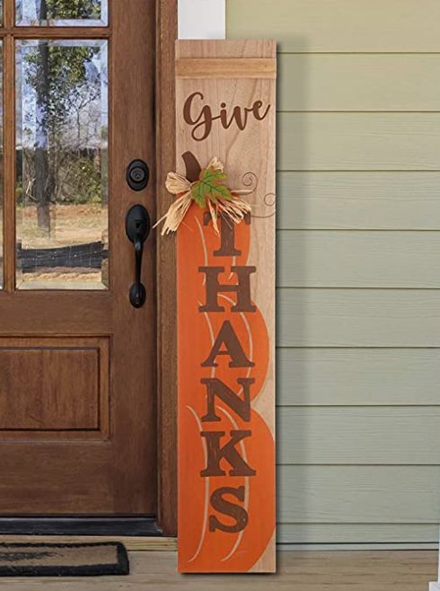 a wooden sign that says give thanks on it in front of a door with a pumpkin