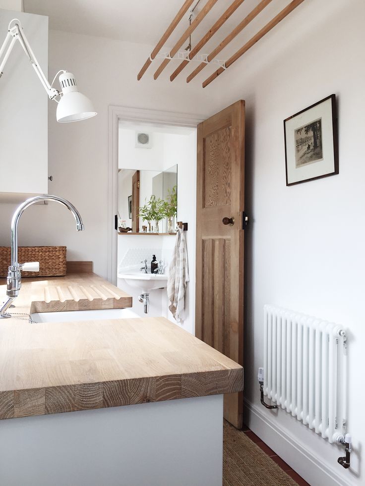 a white kitchen with wooden counter tops and an open door leading to the bathroom area