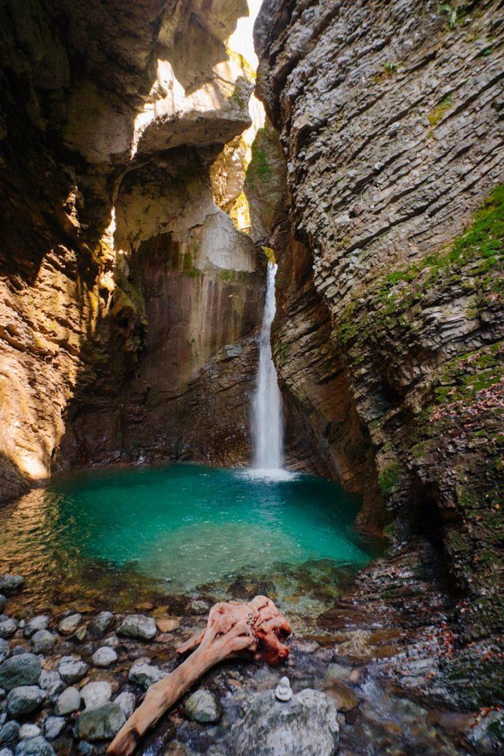 there is a small waterfall in the middle of this canyon with blue water and rocks