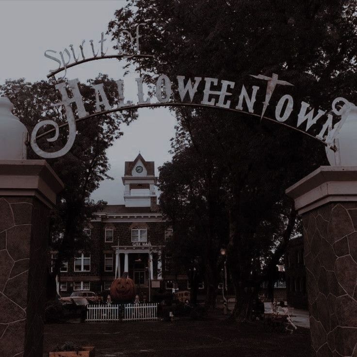 an entrance to a building with a clock tower in the background and trees on either side