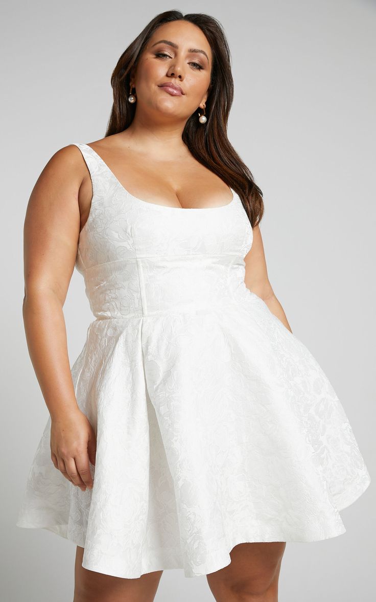 a woman in a white dress posing for the camera with her hands on her hips