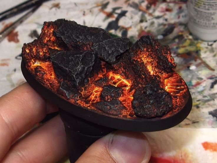 a hand holding a piece of wood that has been lit up with fire and coal