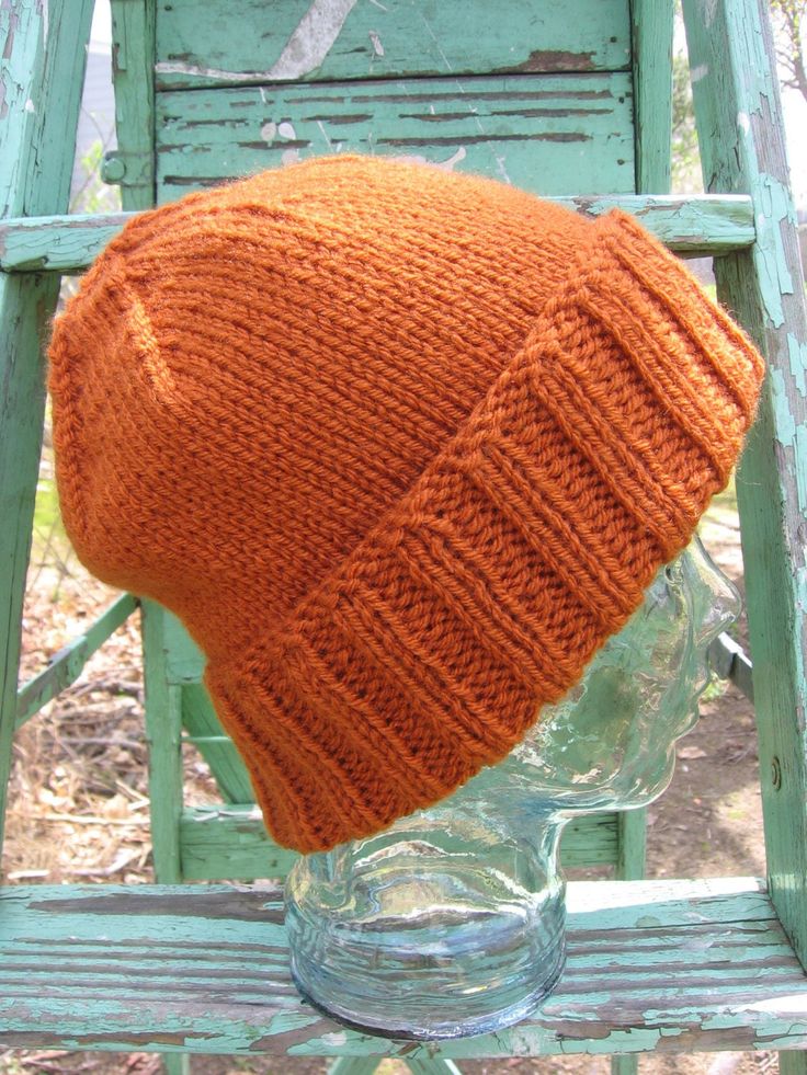 an orange knitted hat sitting on top of a wooden chair