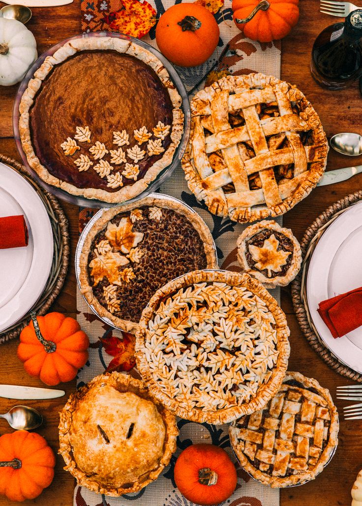 a table topped with lots of pies and pumpkins