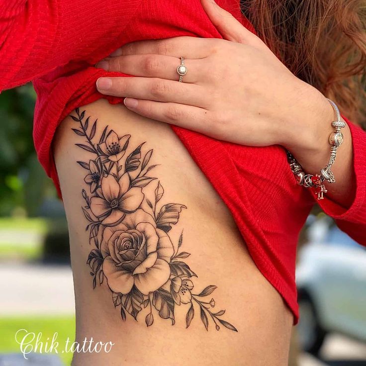 a close up of a woman's stomach with flowers and leaves tattooed on it