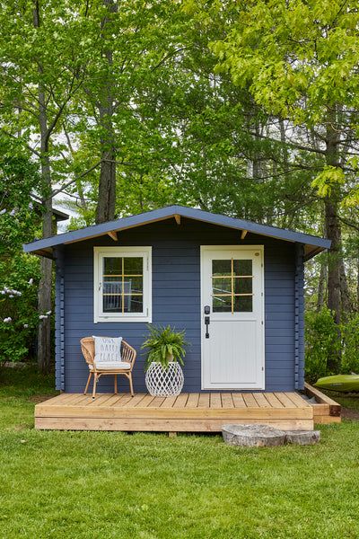 a small blue shed sitting on top of a lush green field