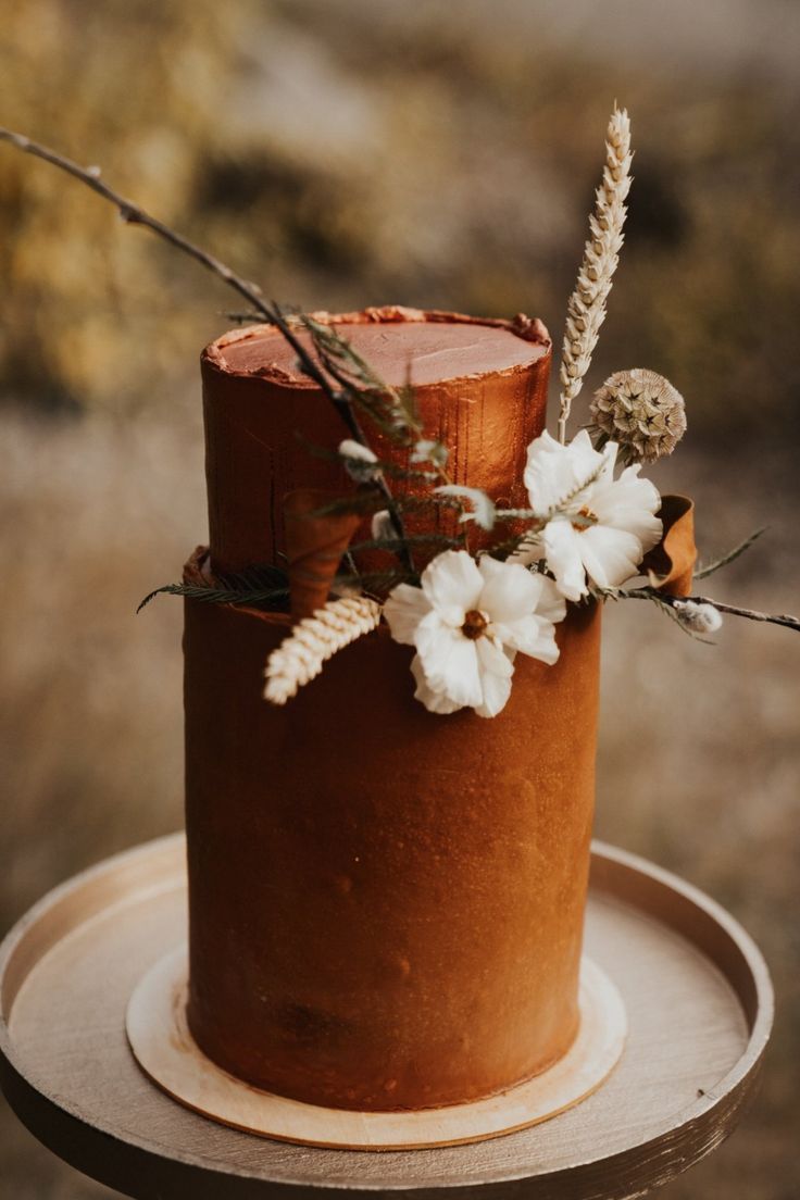 a close up of a cake with flowers and branches on the top, sitting on a table