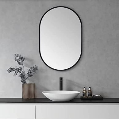 a bathroom with a sink, mirror and plant on the counter in front of it