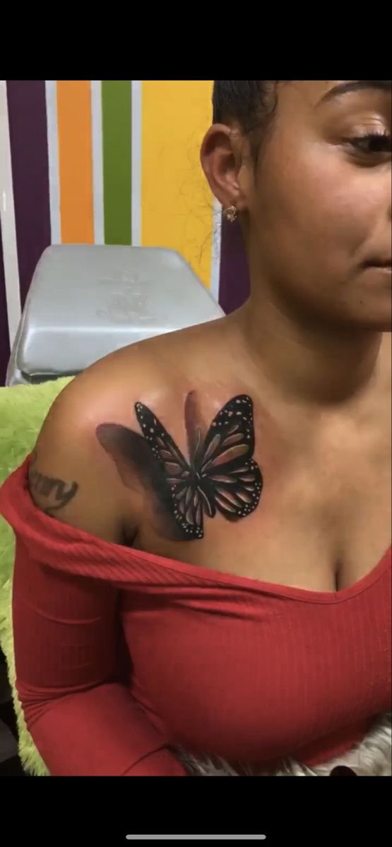 a woman with a butterfly tattoo on her shoulder and chest is looking at the camera