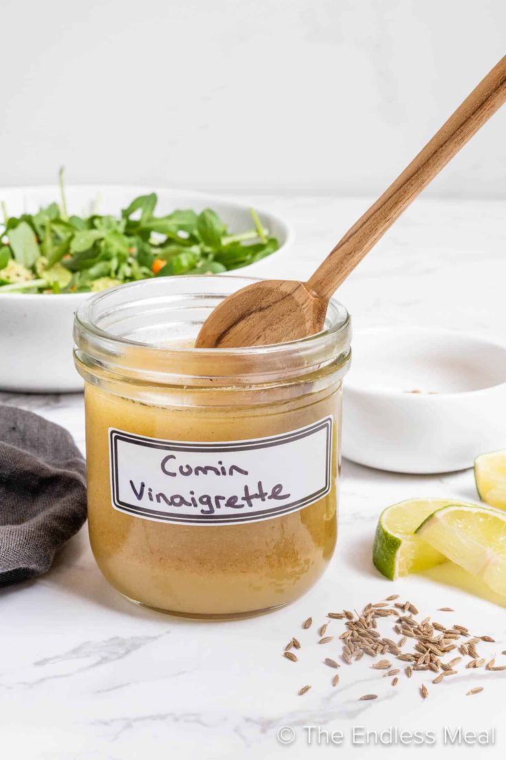 a wooden spoon is next to a jar of cucumber vinaigrette