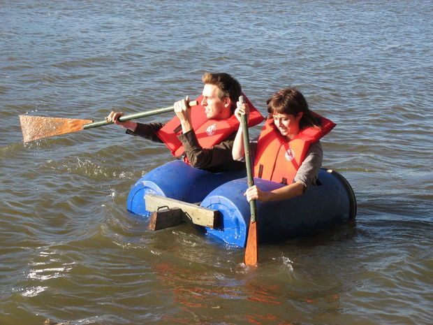 two people in life vests paddling on an inflatable raft with oars