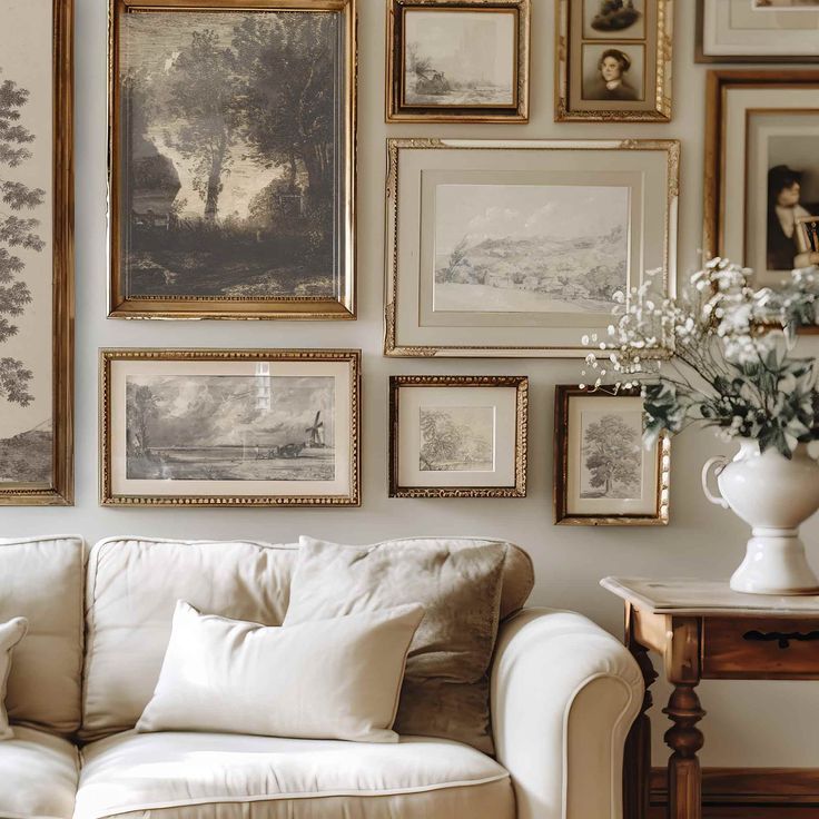 a living room filled with lots of framed pictures on the wall above a white couch