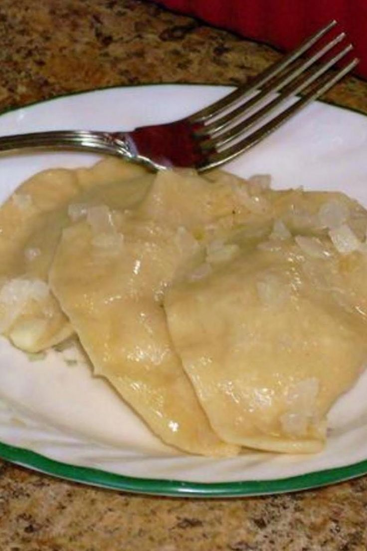 a white plate topped with ravioli on top of a counter next to a fork