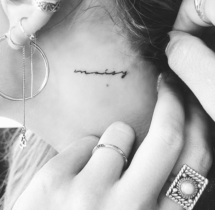 a woman with a small tattoo on her left side behind her ear and the word love is written in cursive font