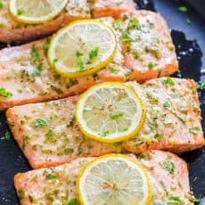 grilled salmon with lemons and herbs on a black plate