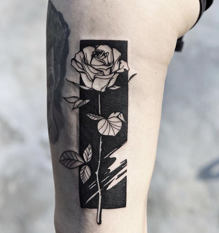 a black and white photo of a rose on the thigh with an ink pen in it