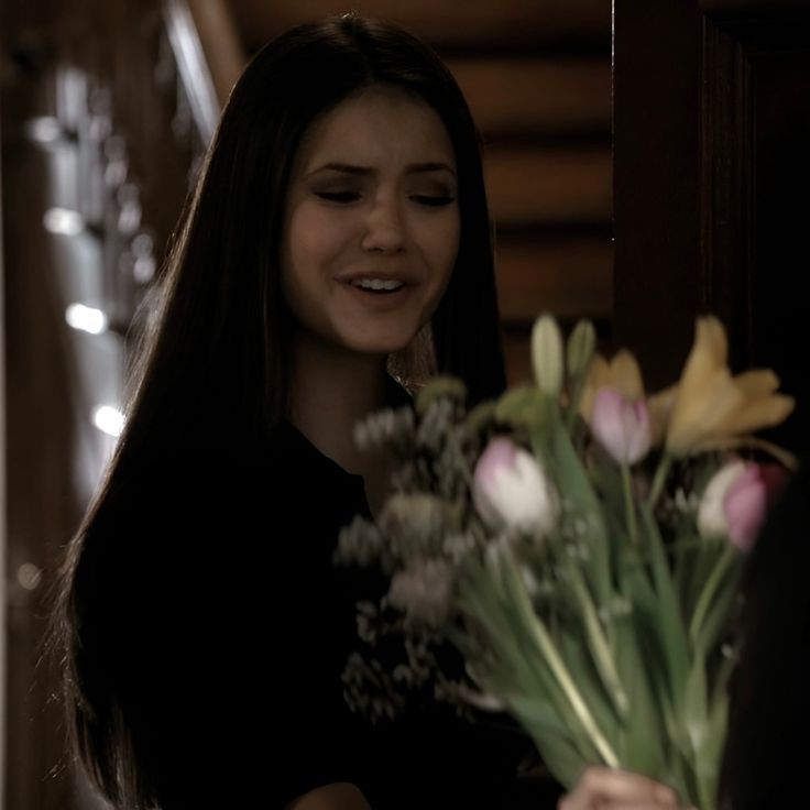 a woman standing next to a vase filled with flowers