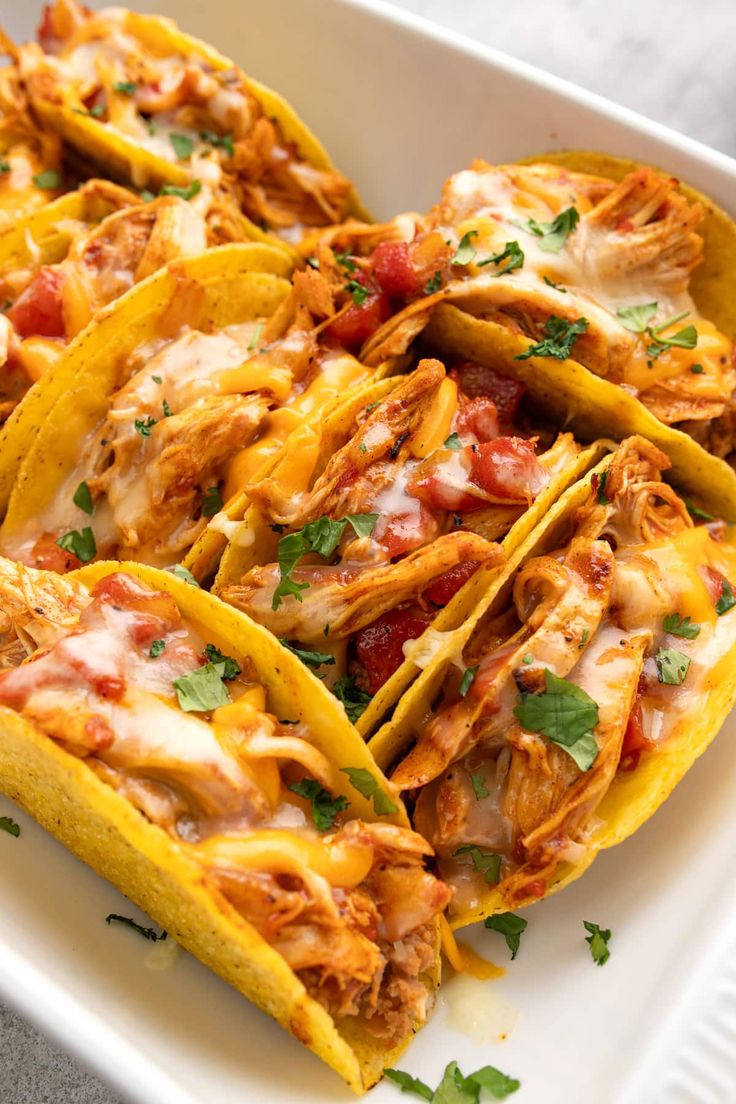 some tacos are sitting in a white dish on a table and ready to be eaten