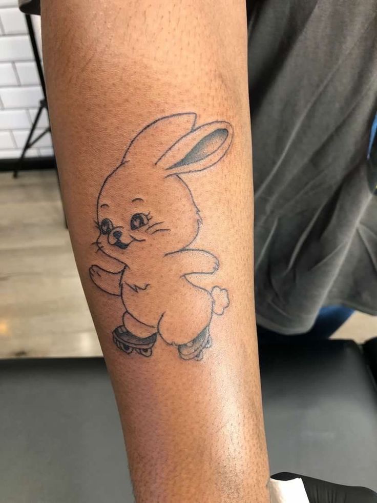 a tattoo on the leg of a person with a small bunny sitting on top of it