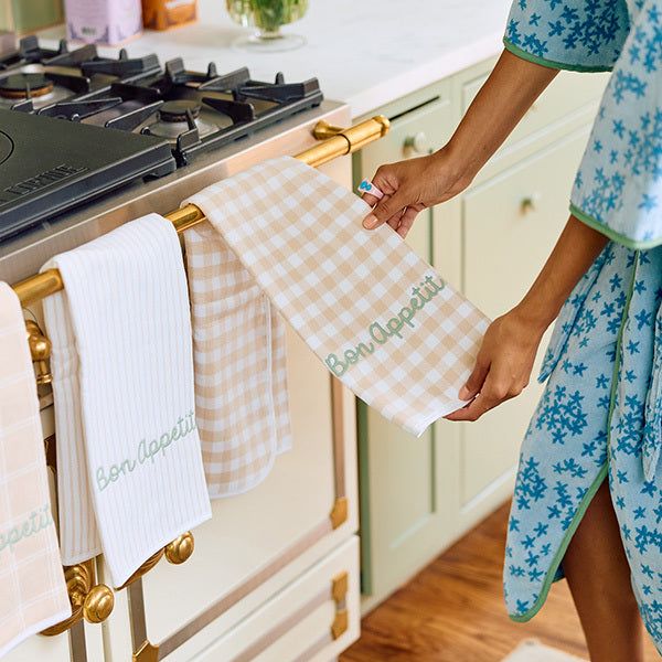 a woman holding two towels in front of an oven