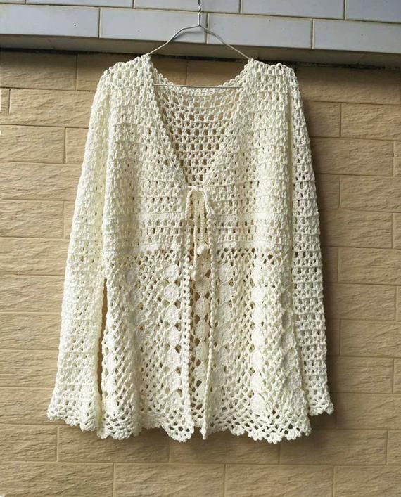 a white crocheted sweater hanging on a brick wall