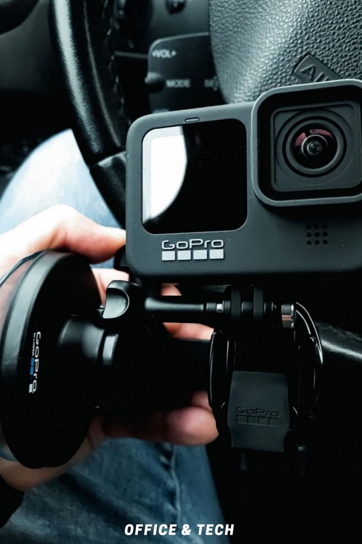 a person holding a camera in their hand while sitting in a car with the steering wheel behind them