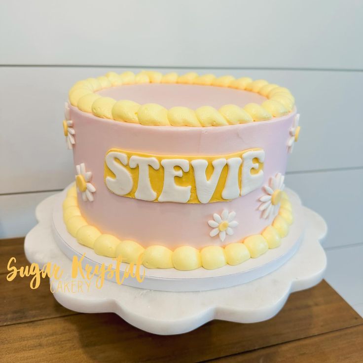 a pink and yellow cake sitting on top of a wooden table