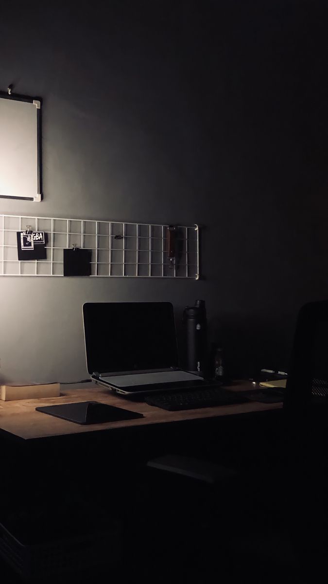 a laptop computer sitting on top of a wooden desk next to a lamp and chair