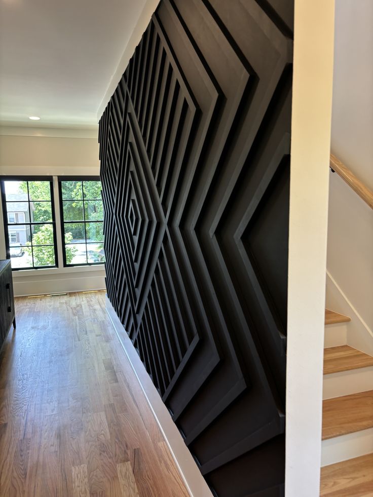 a room with wooden floors and black wall covering the entire area, along with a stair case