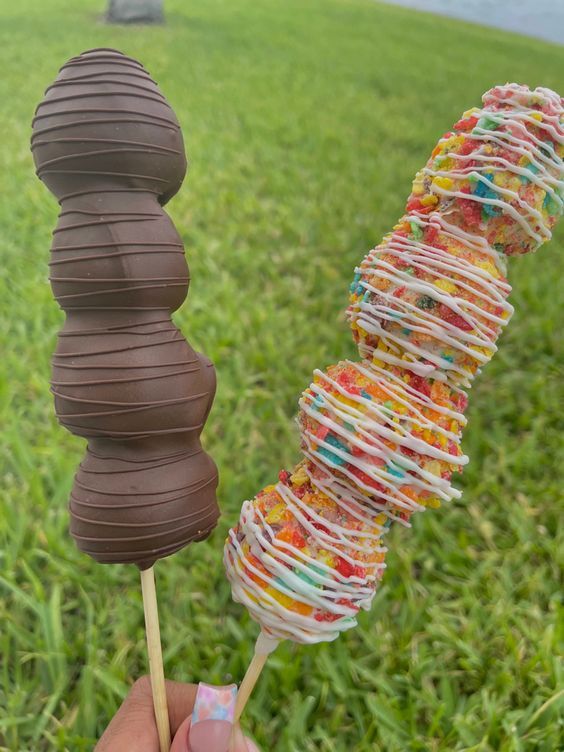 a hand holding a chocolate covered candy lollipop