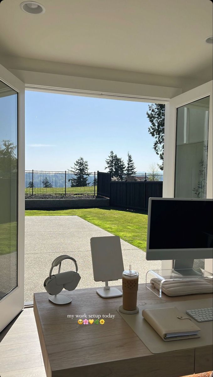 a desk with a computer on top of it in front of a sliding glass door