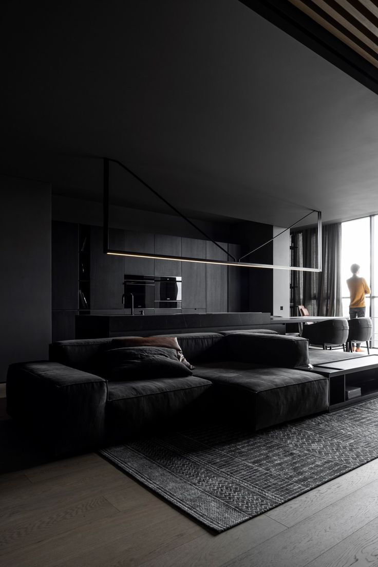 a living room filled with black furniture next to a large glass window on top of a hard wood floor