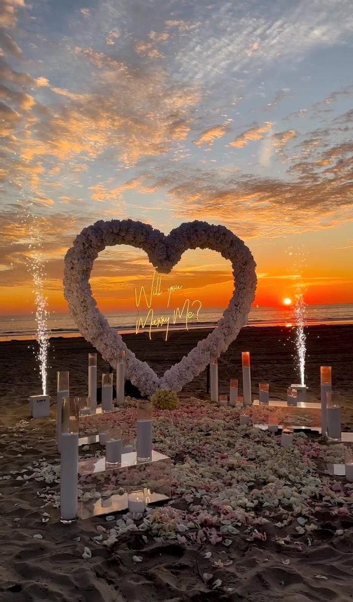 a heart made out of flowers sitting on top of a beach