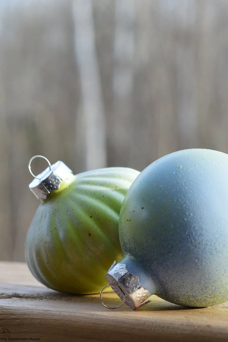 two green and blue ornaments sitting on top of a wooden table