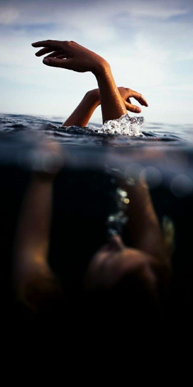 someone is swimming in the ocean with their hand up to the water's surface