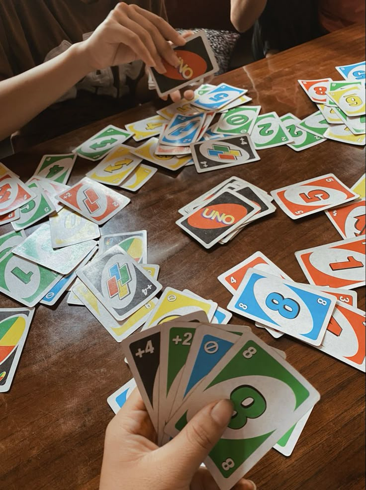 a person holding up cards on top of a wooden table