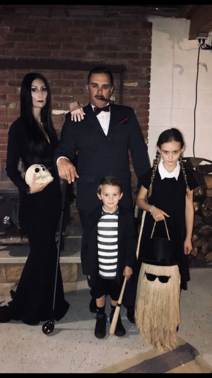 a family dressed up for halloween standing in front of a fire place with brooms