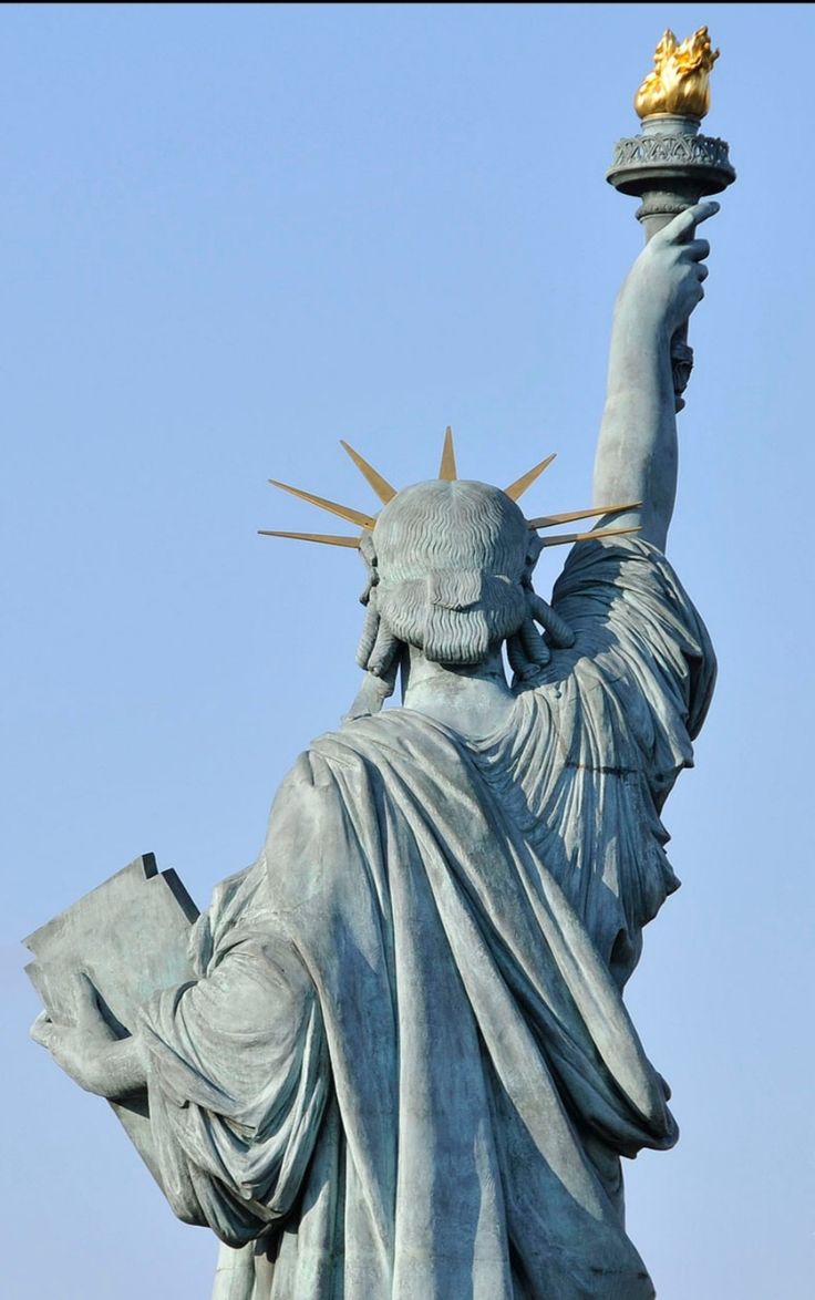 the statue of liberty is holding a book in her hand and wearing a gold crown