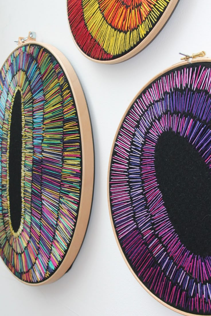 three handmade hoops with colorful designs on them